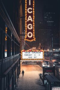 A person walks past a theater marquee at night.