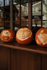 Three carved pumpkins sit on a windowsill.