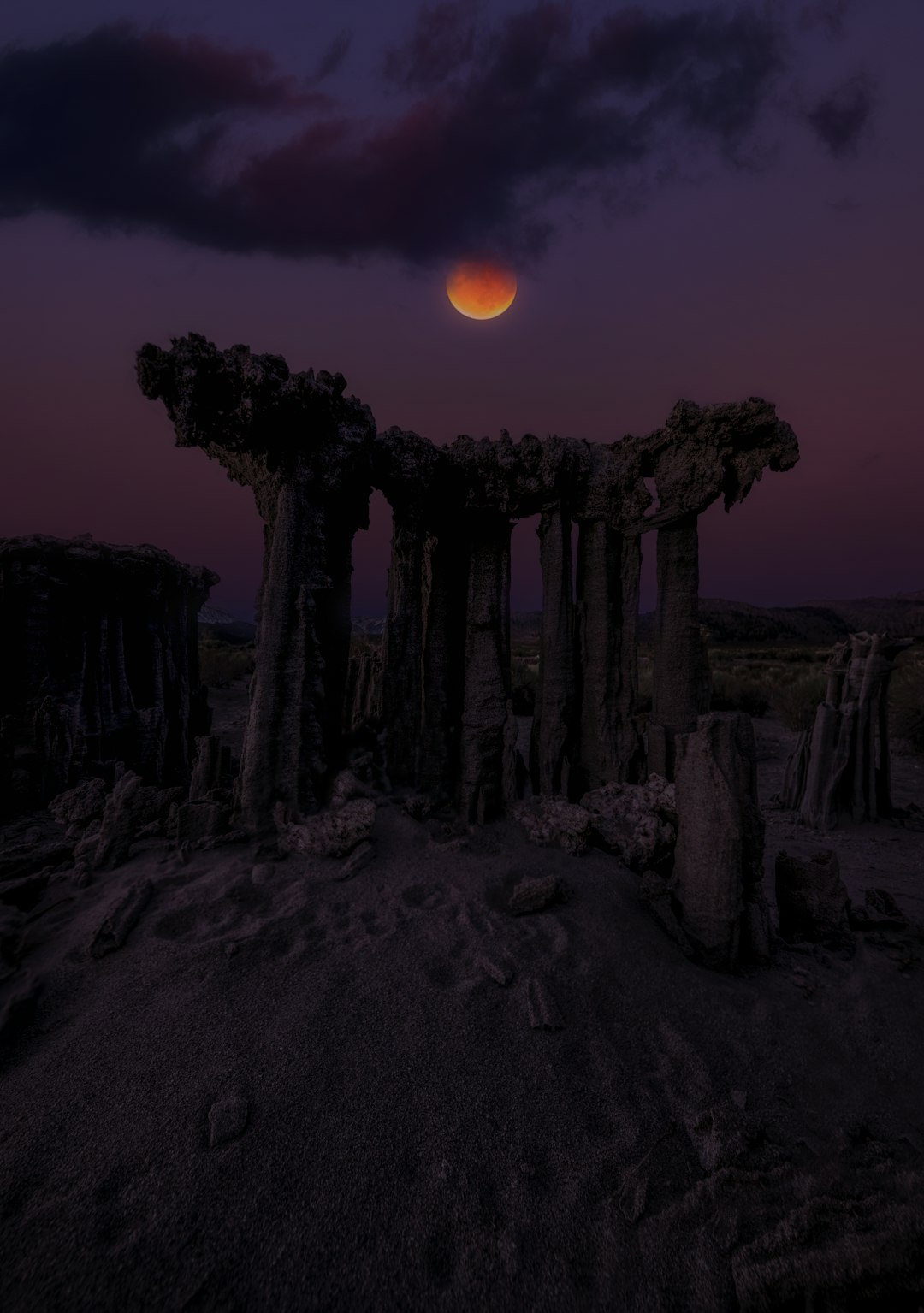 Blood moon over strange rock formations at dusk